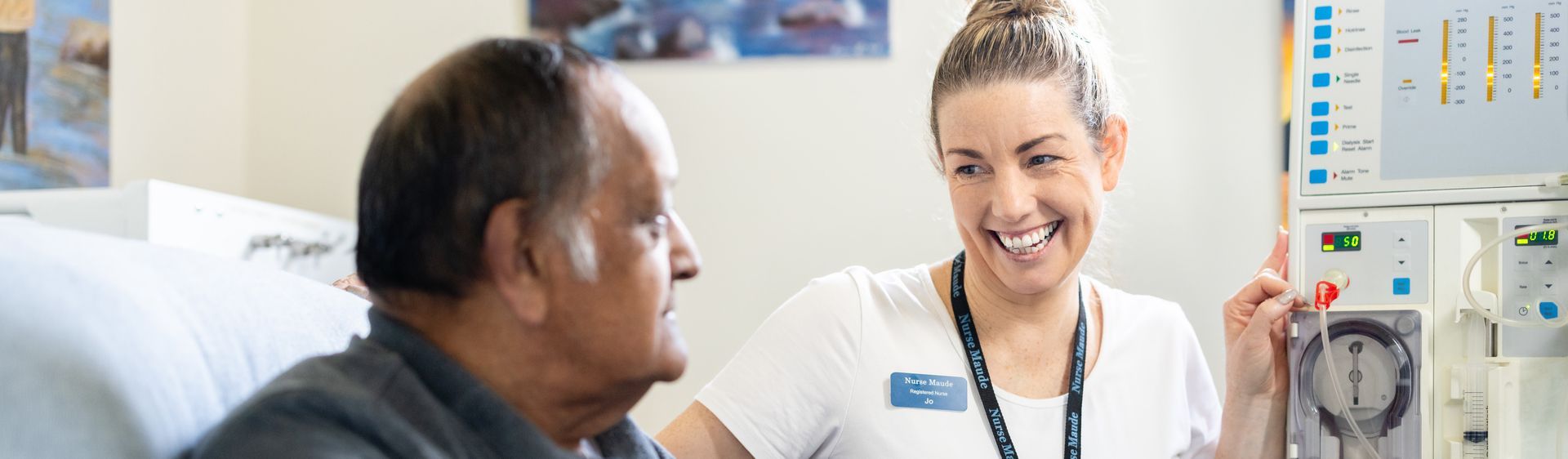 A nurse is talking to an elderly man in a hospital bed
