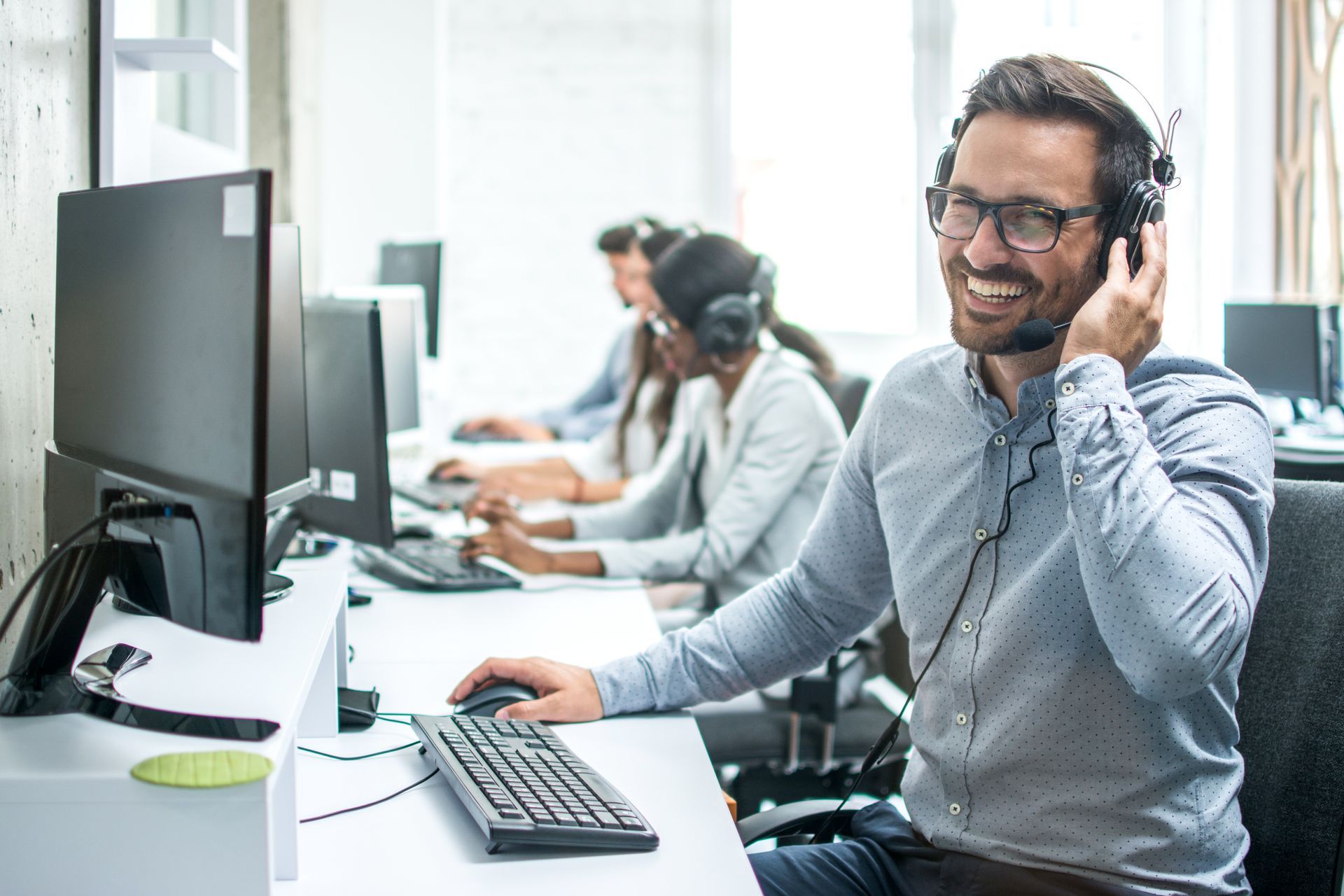 A man wearing headphones is sitting at a desk in front of a computer.