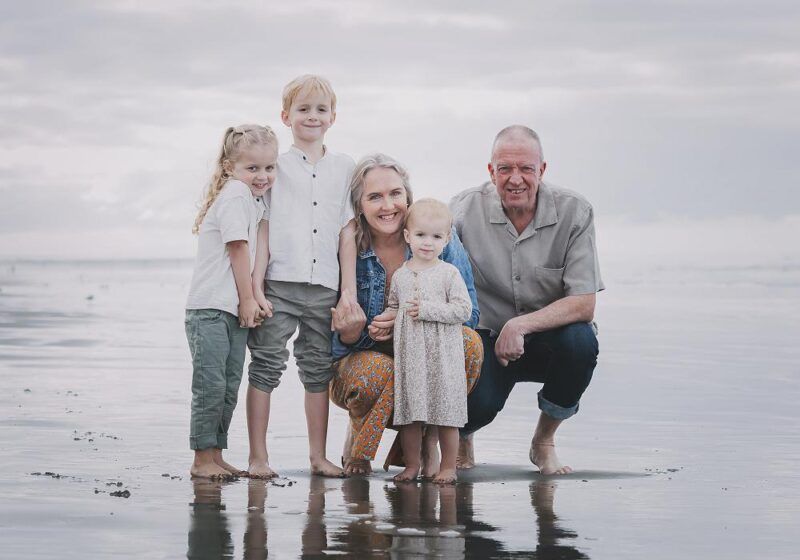 A family is posing for a picture on the beach.