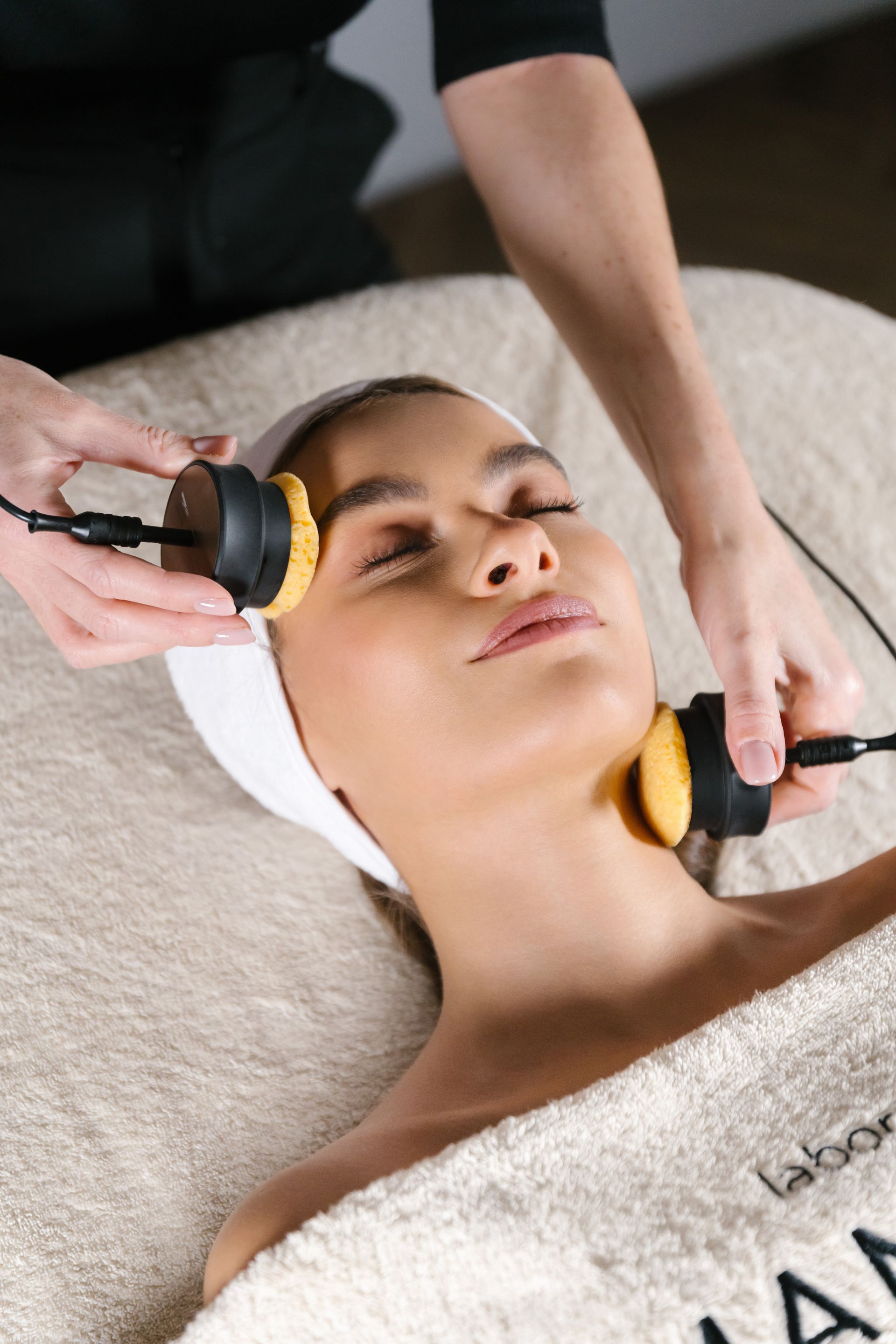 Femme recevant un soin du visage avec deux appareils.