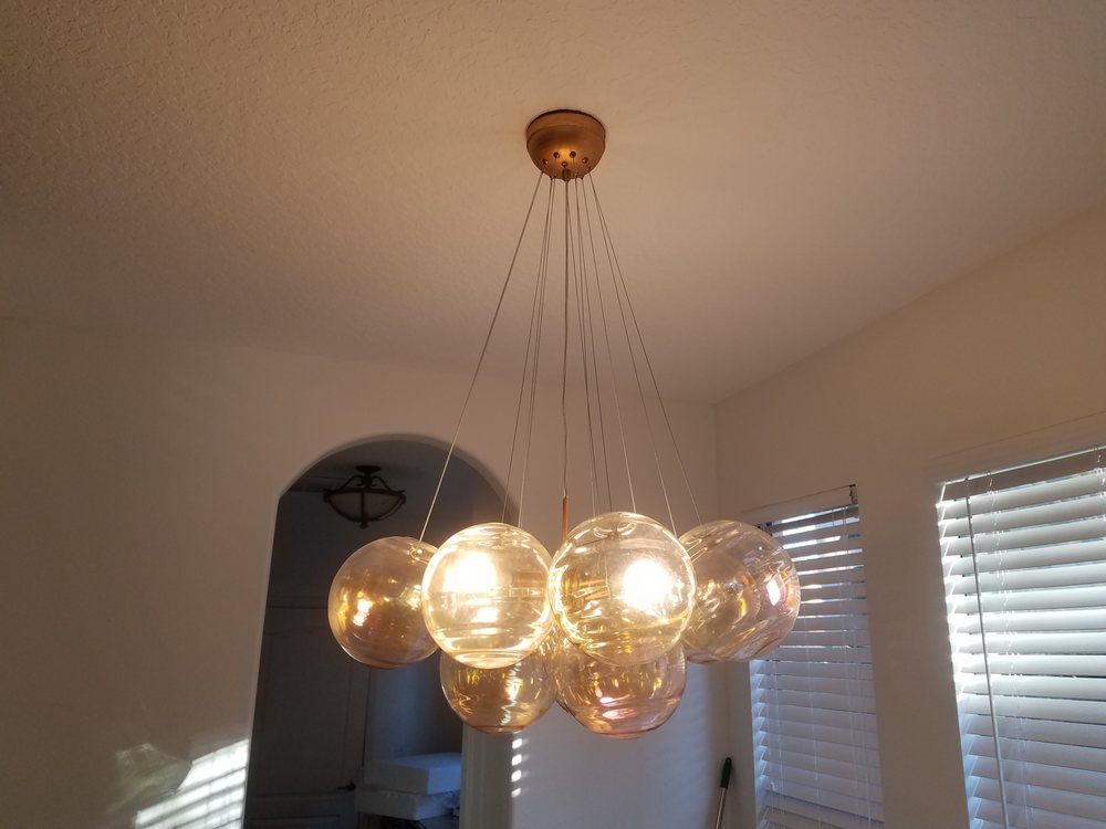 A gold-toned multi-pendant chandelier with spherical glass shades hanging from a ceiling in a residential room.