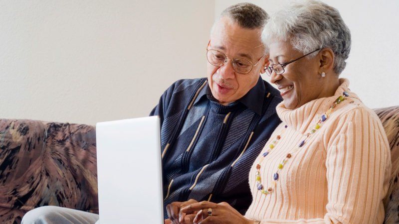 two older people looking at a laptop