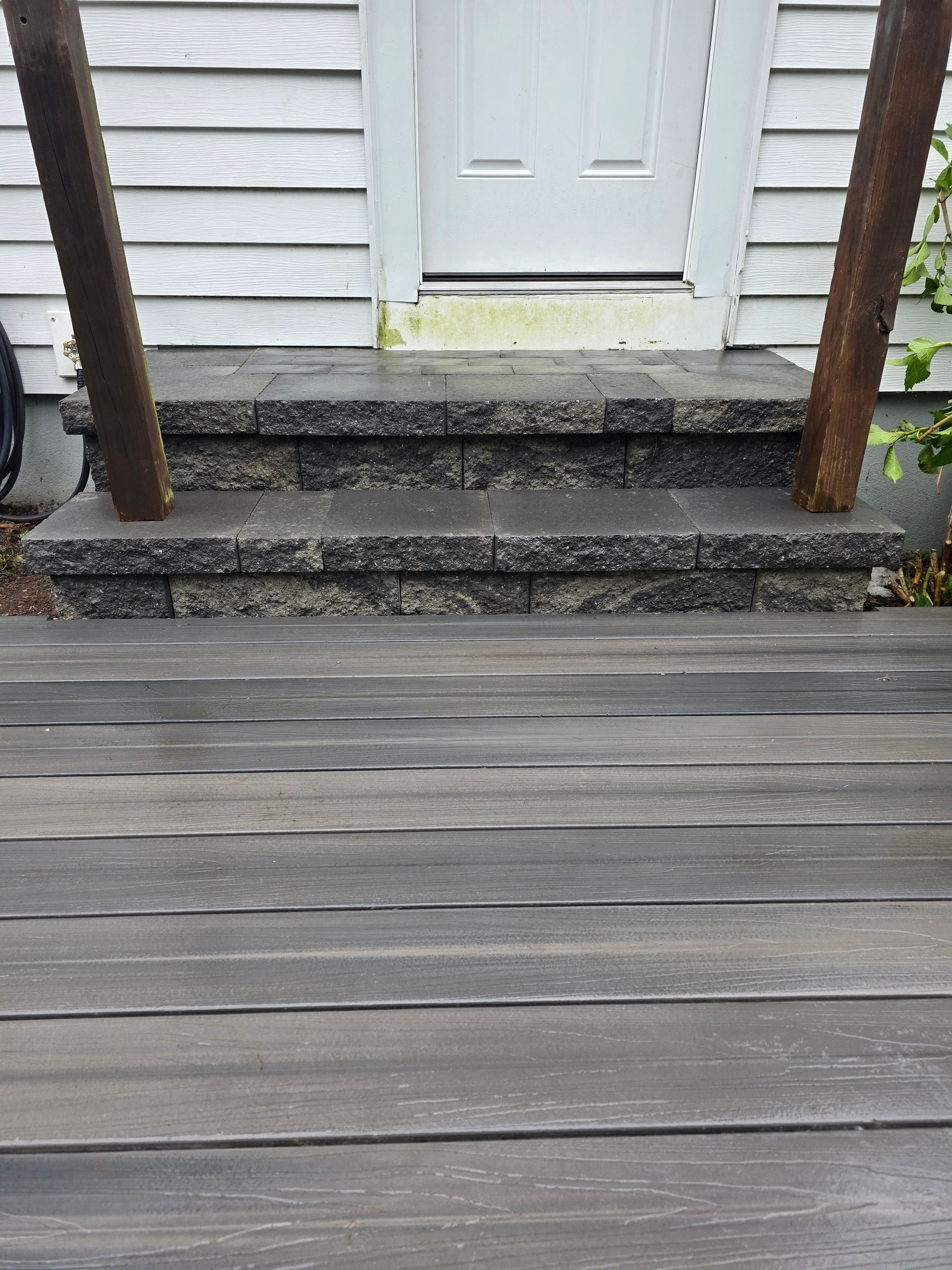 A wooden deck with steps leading up to a white door.