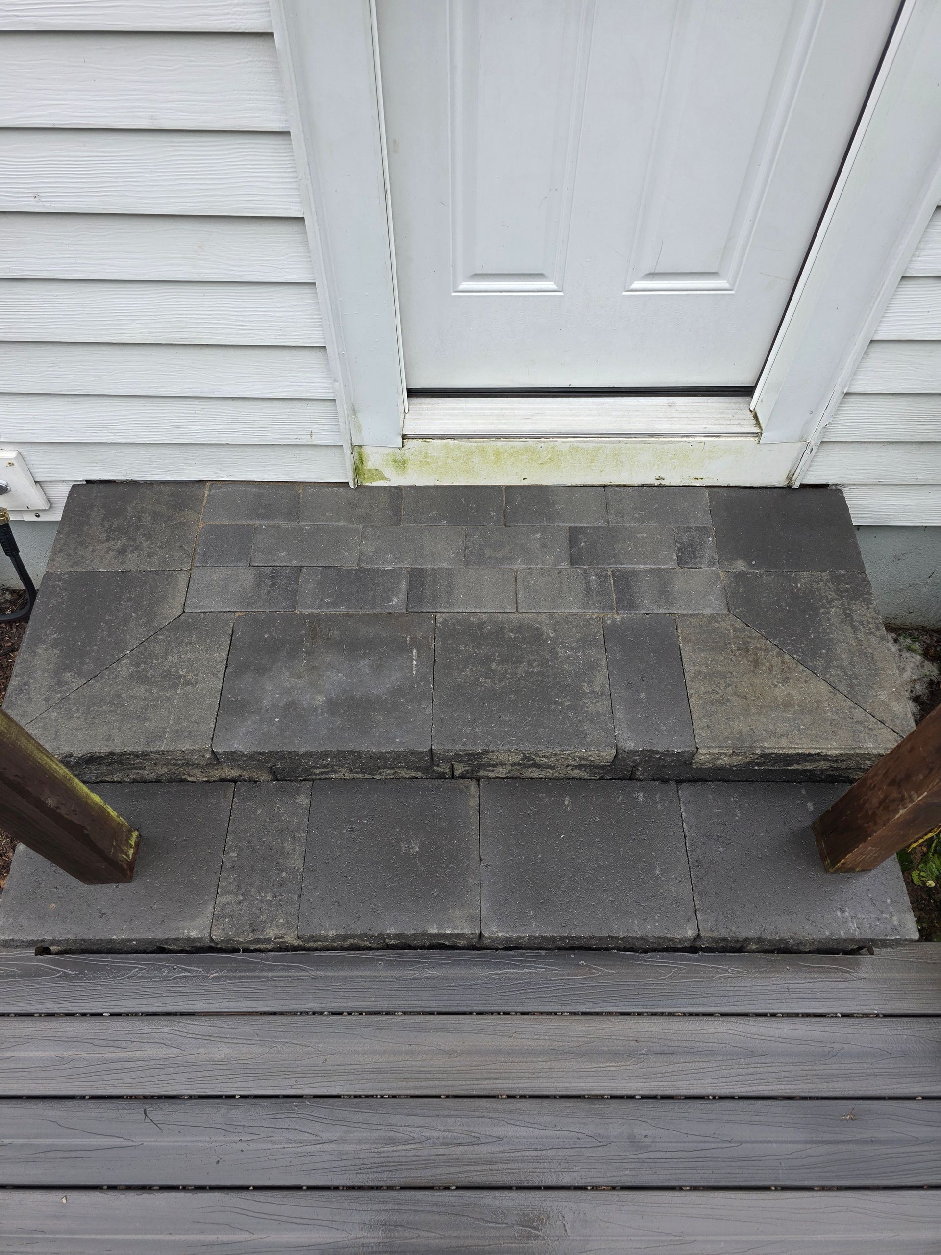 A wooden deck with steps leading up to a white door.