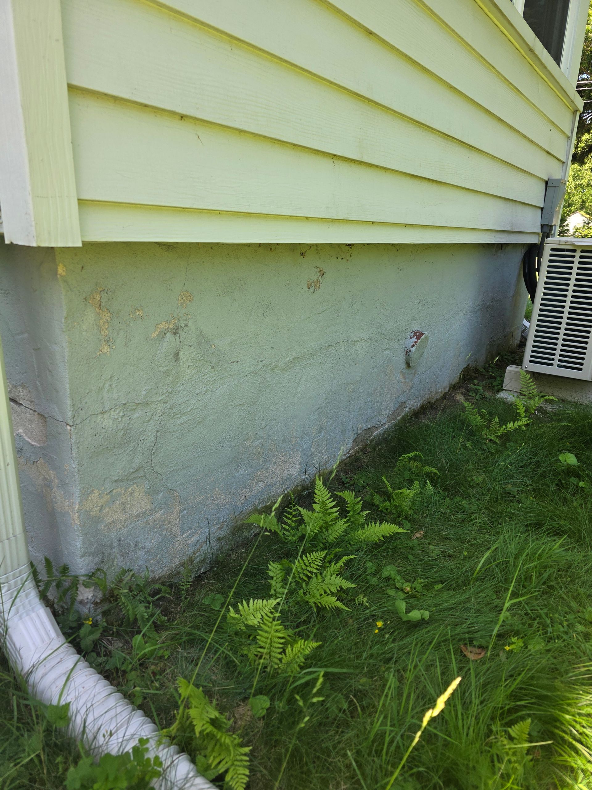 The side of a house with a drain pipe coming out of it.