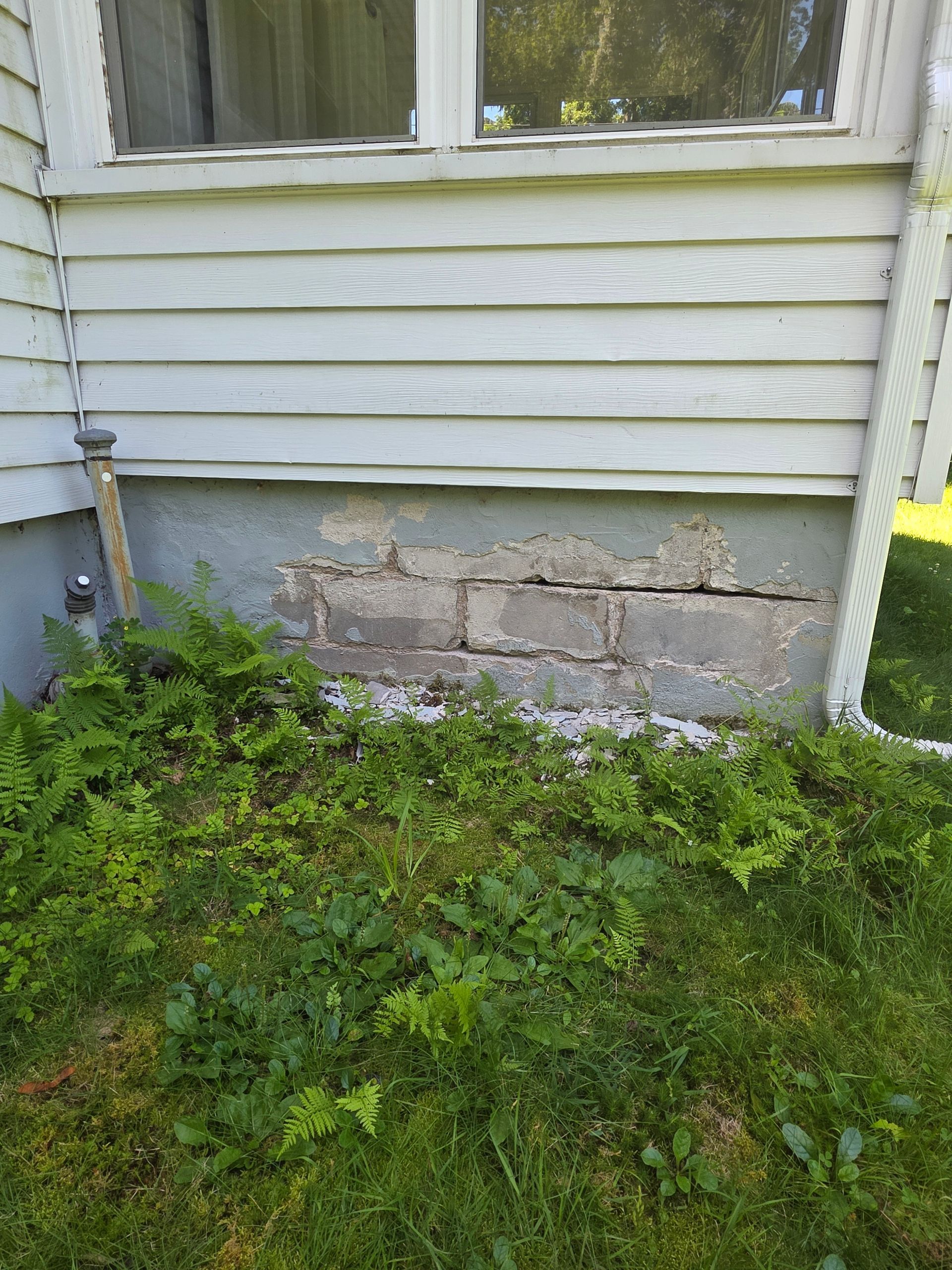 The side of a house with a brick wall and a window.
