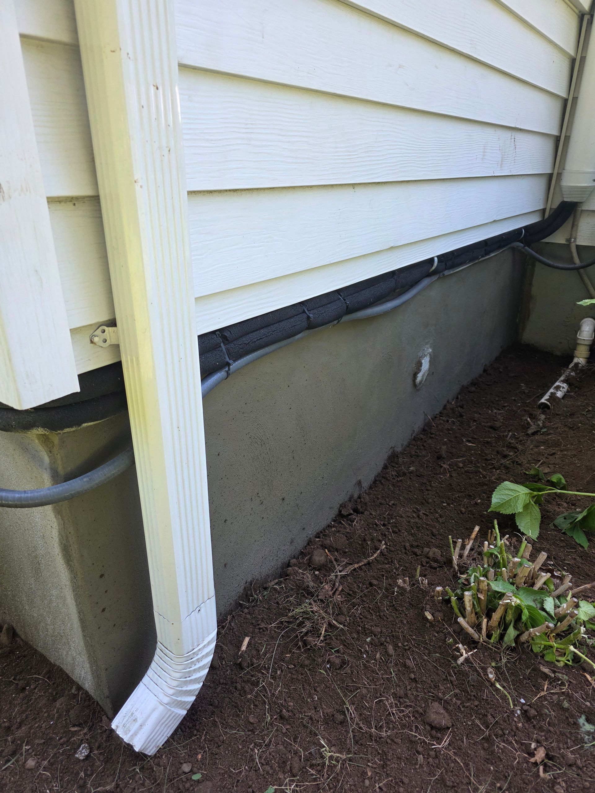 A white house with a gutter on the side of it.