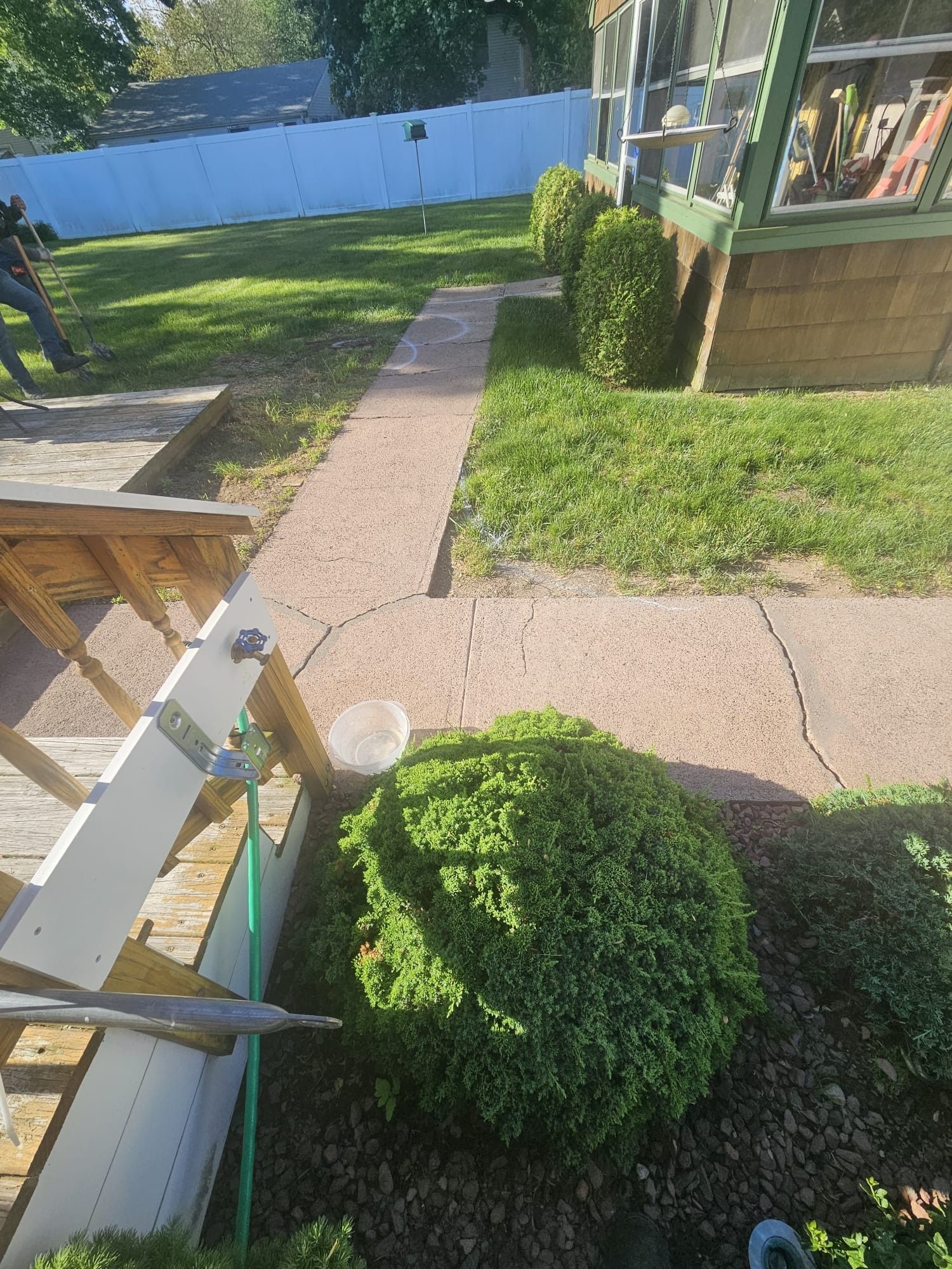 A ladder is sitting on the sidewalk in front of a house.
