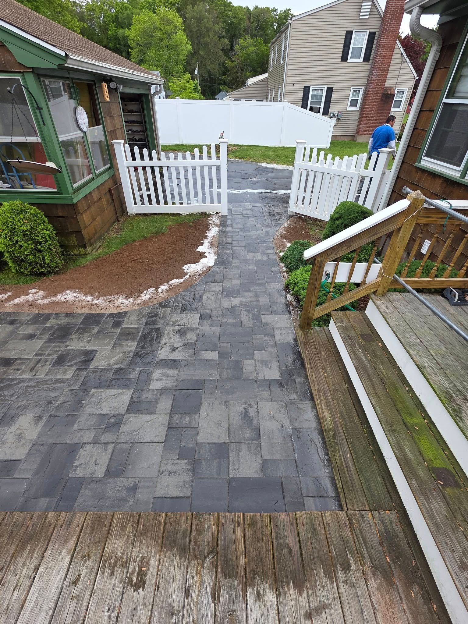 A walkway leading to a house with a white picket fence.