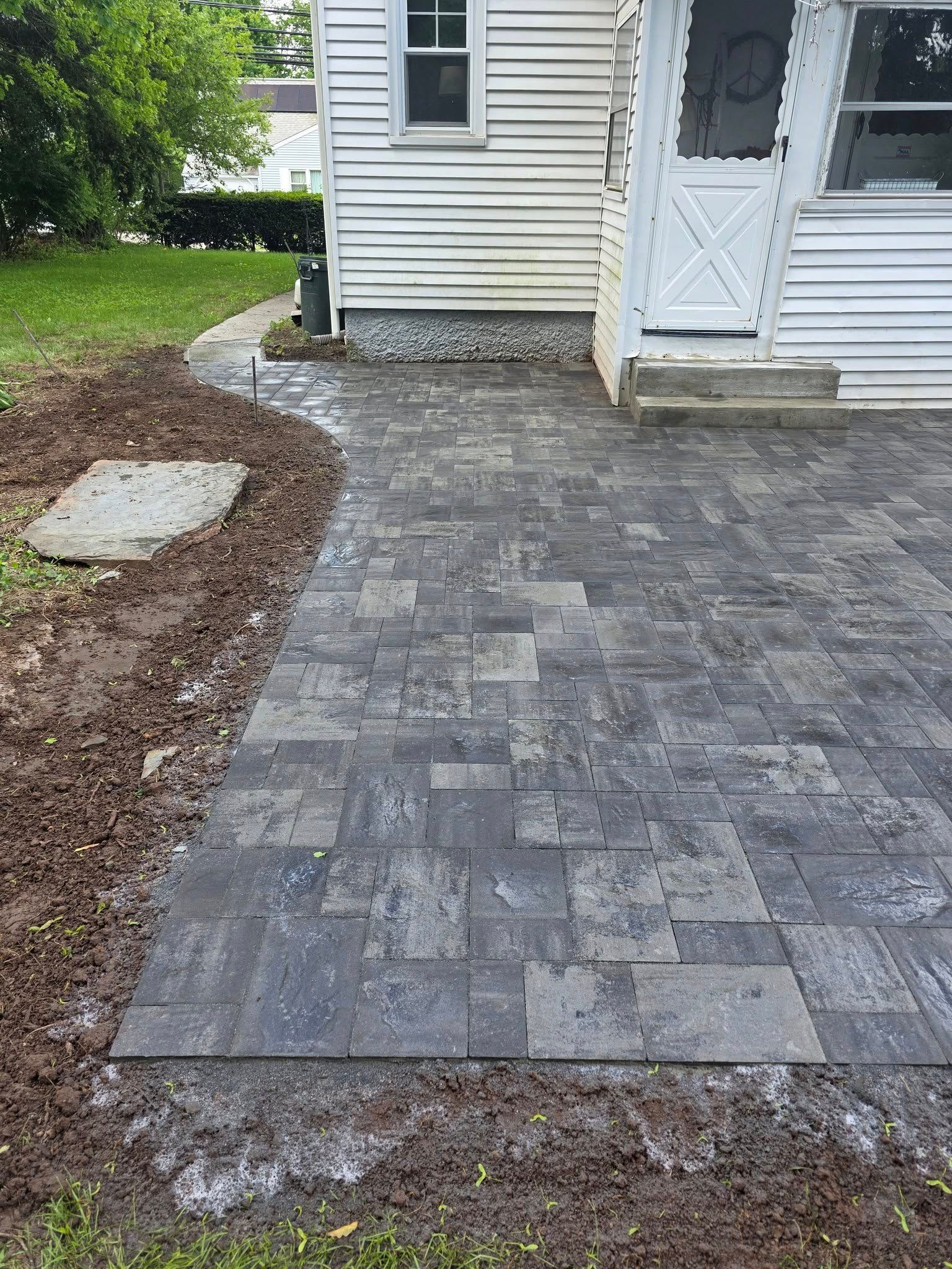 A brick walkway leading to a white house.