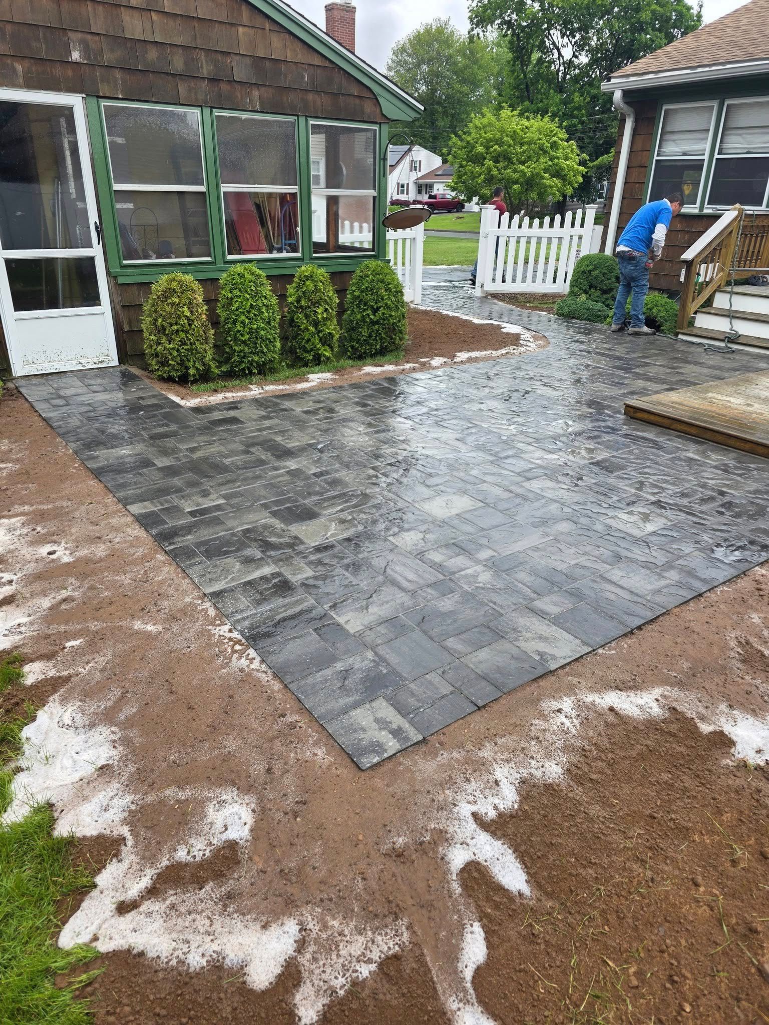 A man is working on a patio in front of a house.