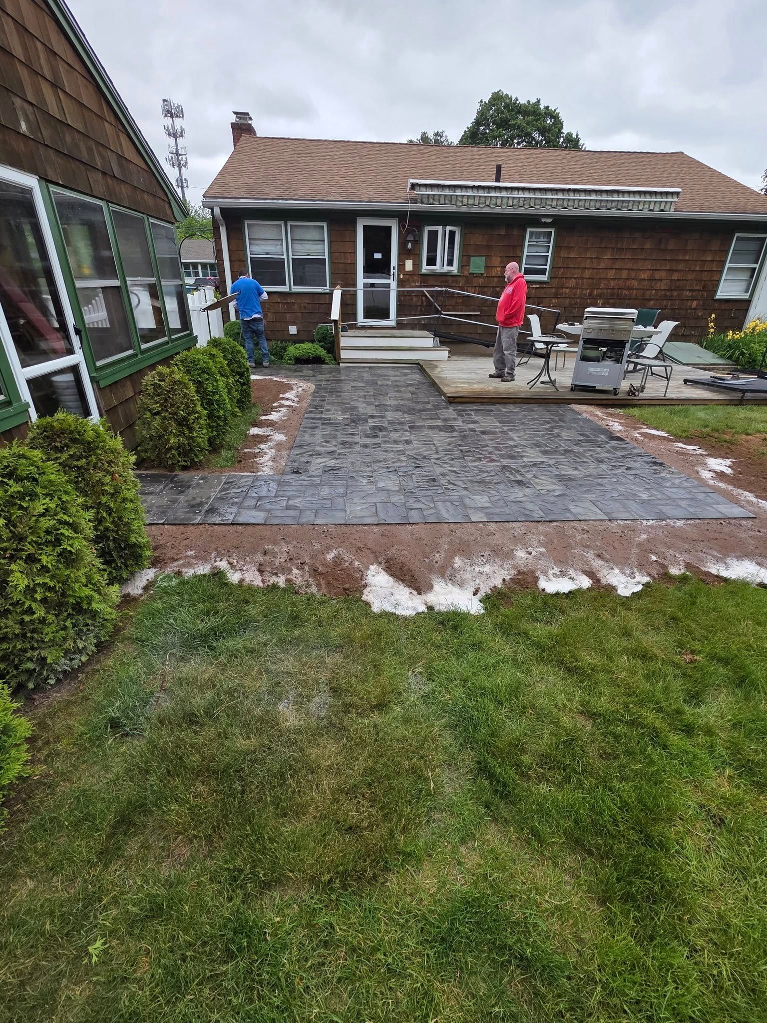 A group of people are working on a patio in front of a house.