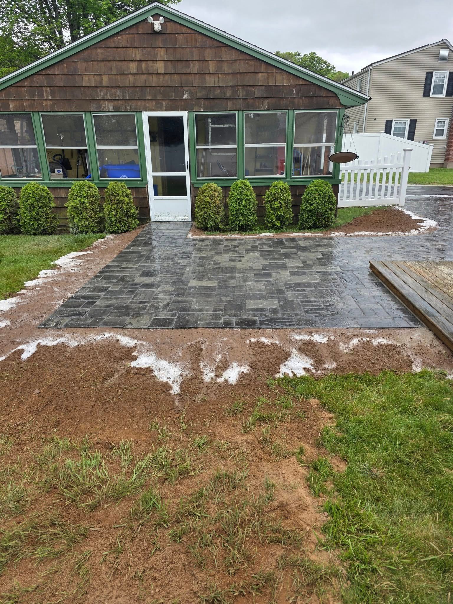 A house with a screened in porch and a patio in front of it.