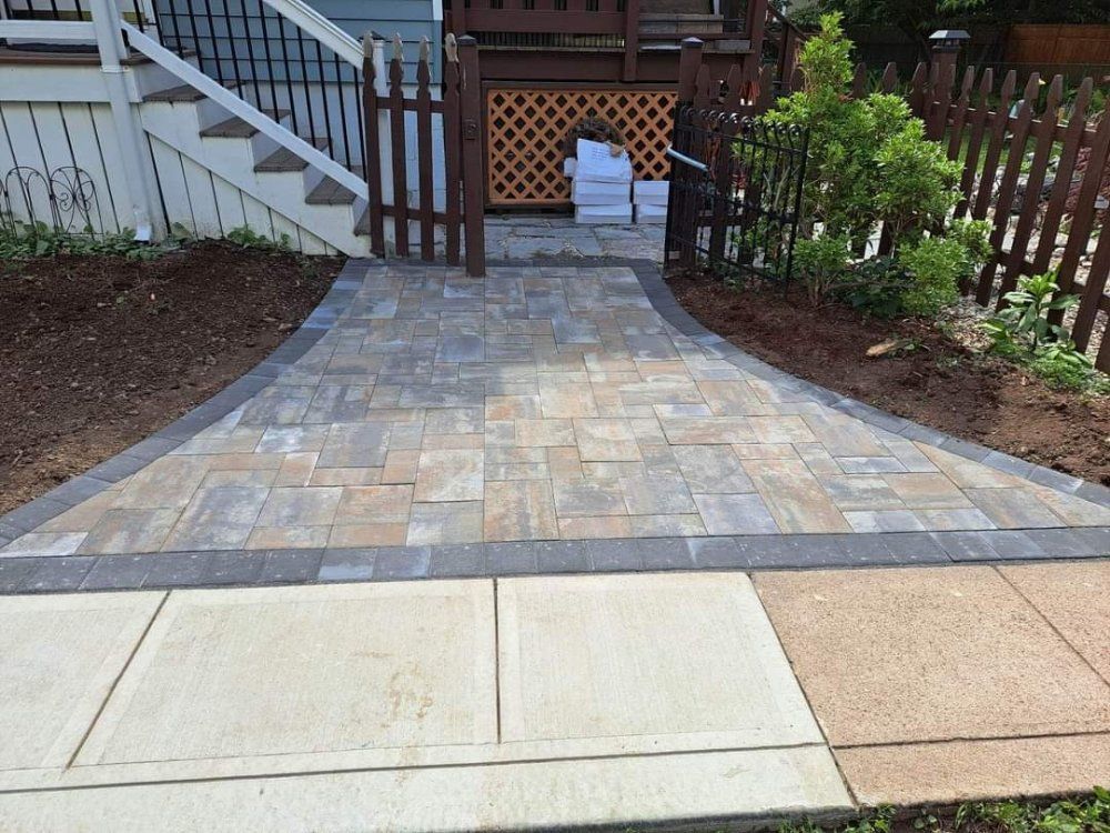 A brick walkway leading to a house with stairs and a gate.