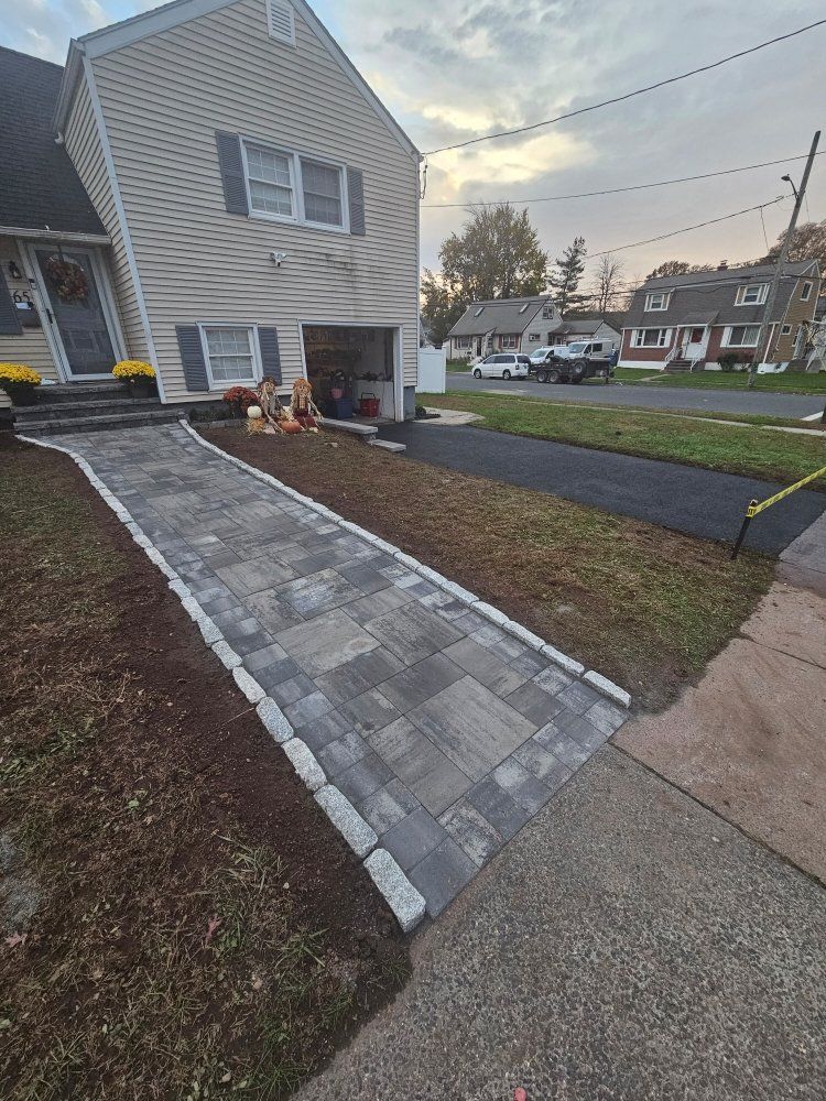 A brick walkway leading to a house with a garage.