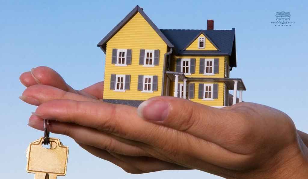 A person is holding a model house and keys in their hands.