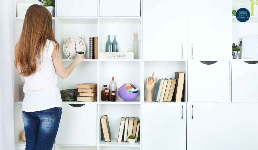 A woman is standing in front of a bookshelf in a room.