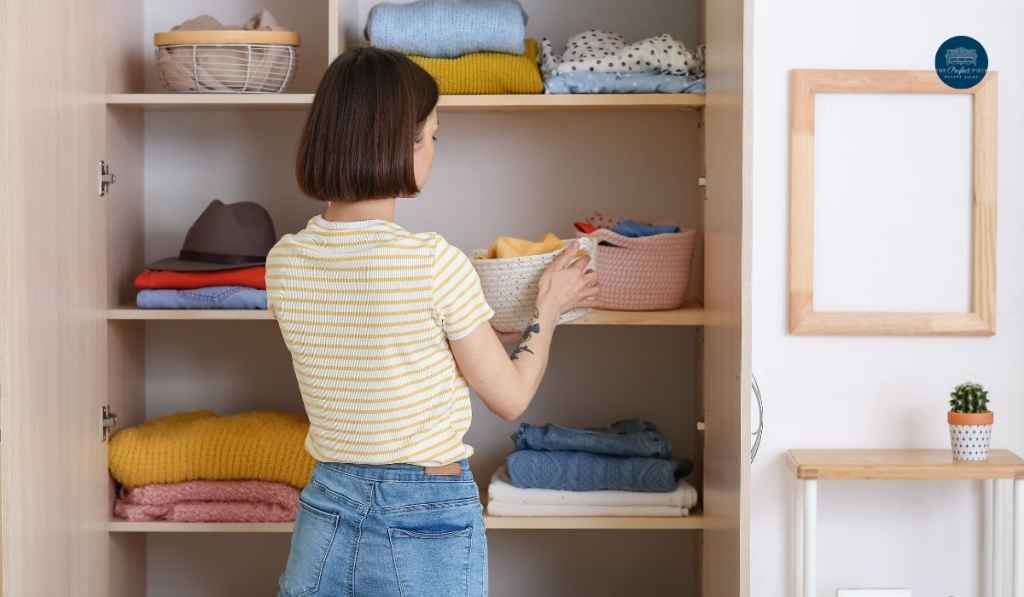 A woman is arranging her clothes in a closet.