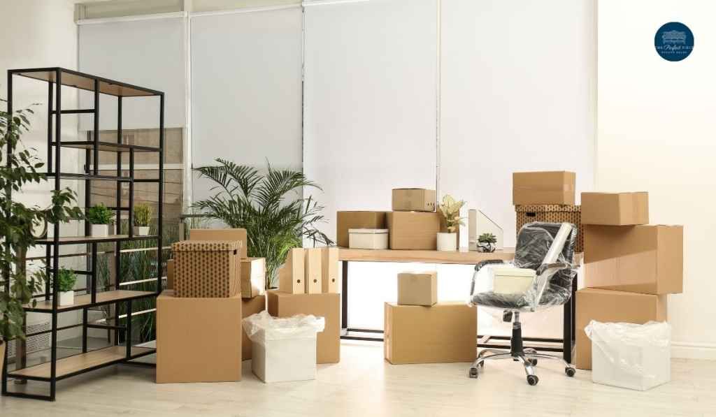 A room filled with boxes , a desk and a chair.