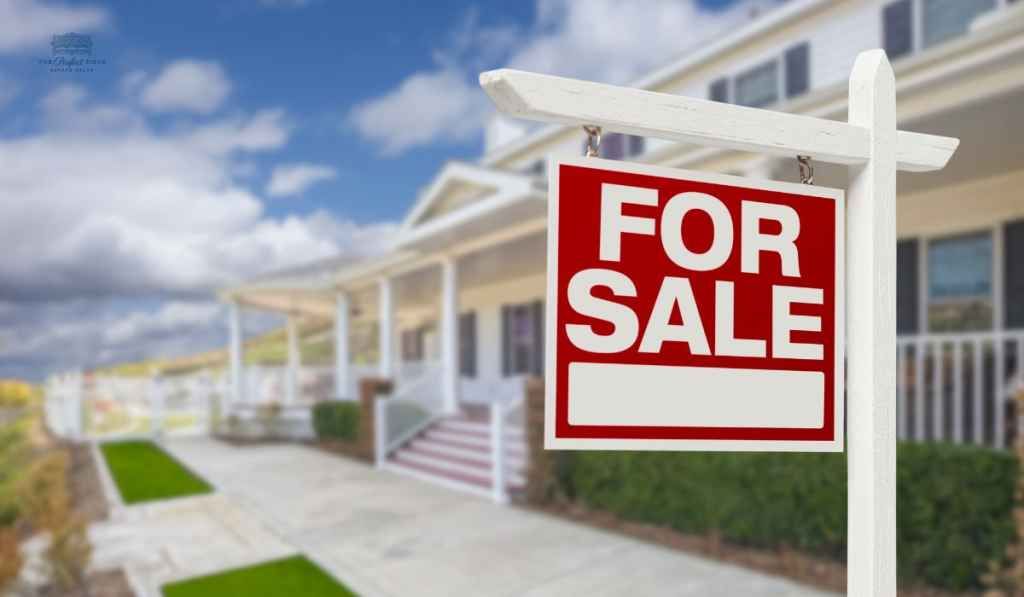 A for sale sign is in front of a house.