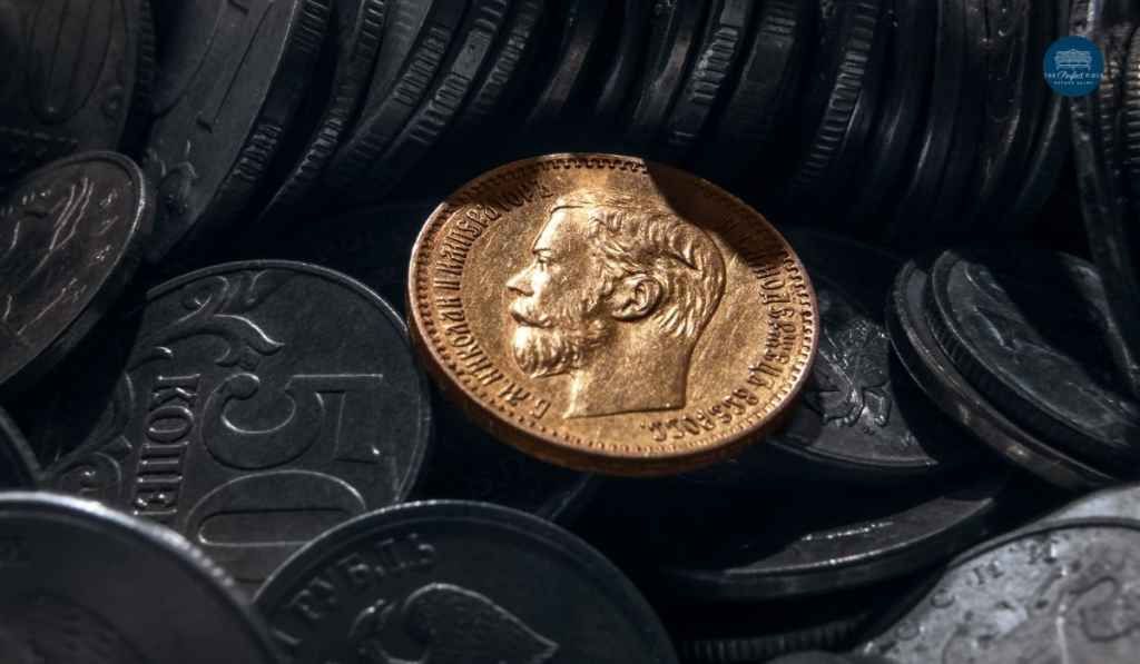 A gold coin is sitting on top of a pile of silver coins.