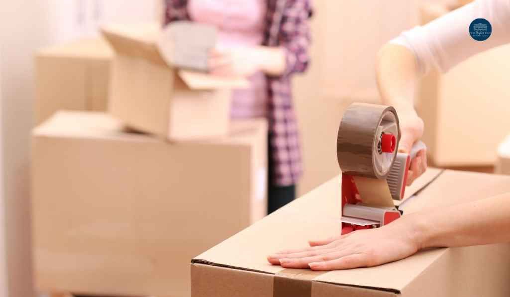 A person is taping a cardboard box with tape.