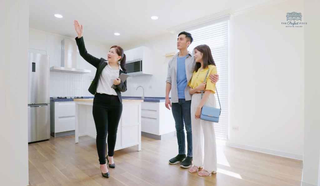 A woman is showing a man and woman a kitchen in a house.