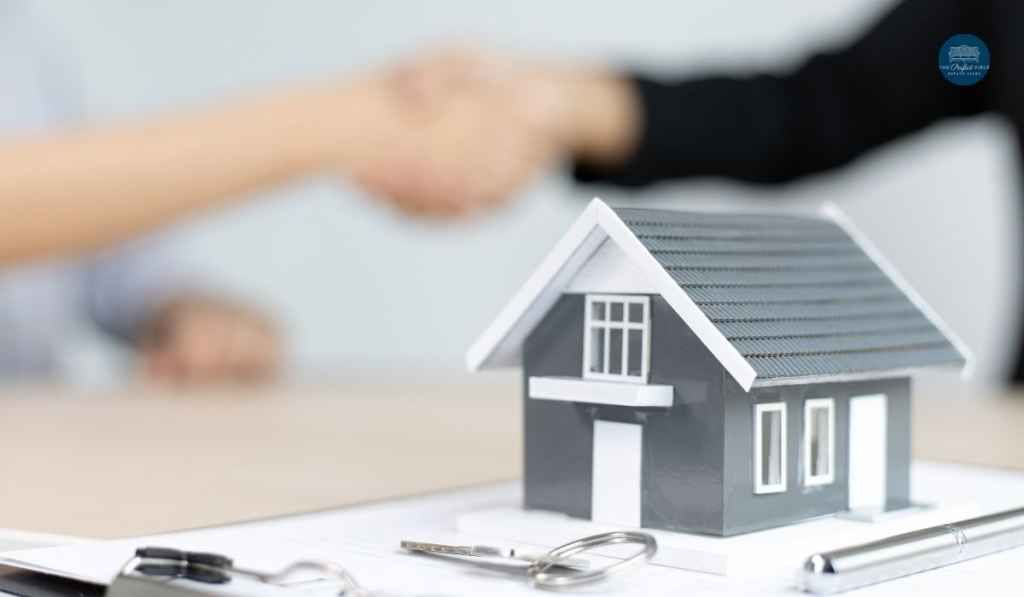 A person is shaking hands next to a model house and keys.