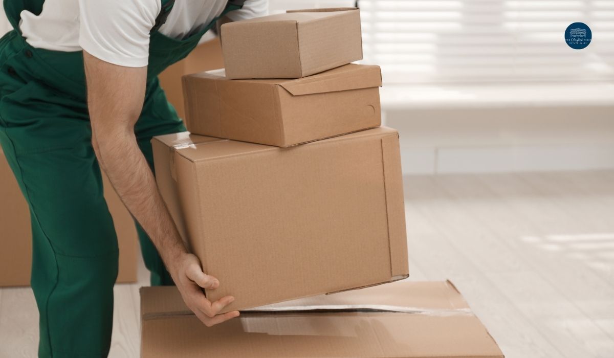 A man is lifting a stack of cardboard boxes.