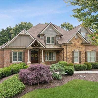 Brick and stone house with brown roof and landscaping.