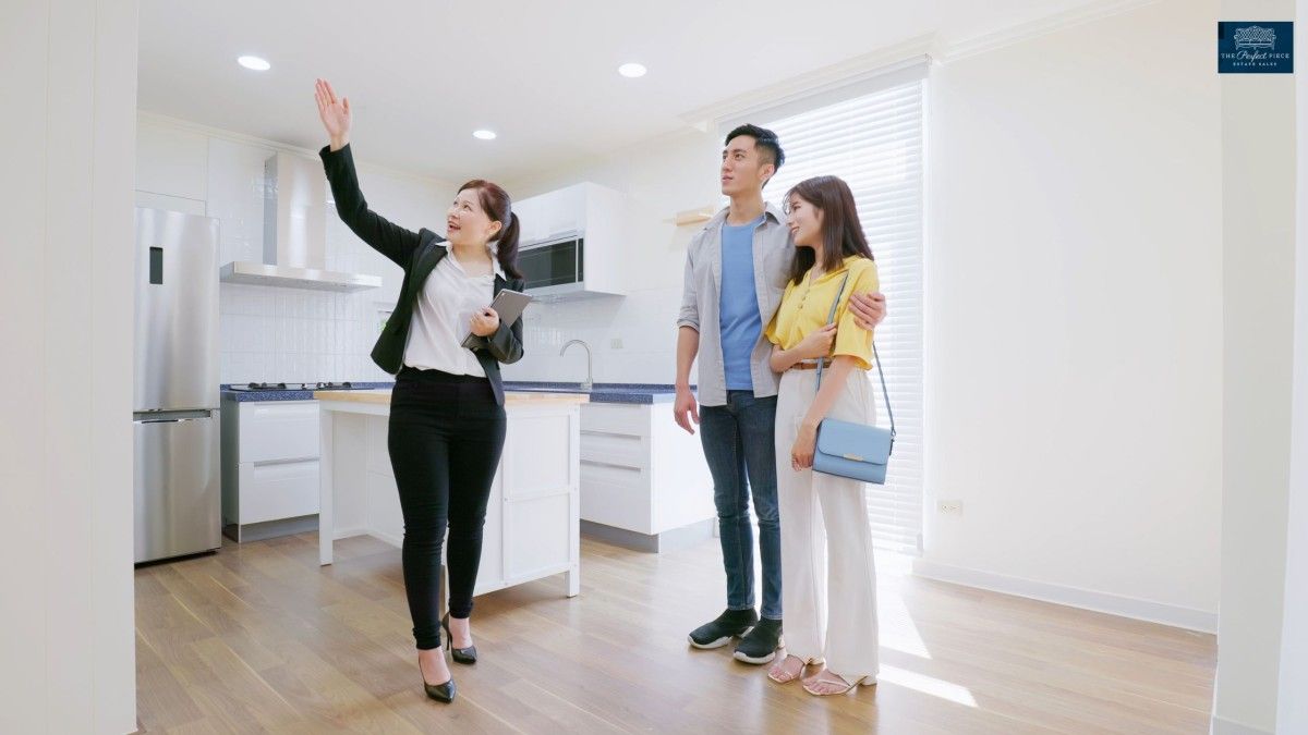 A woman is showing a couple a kitchen in a house.