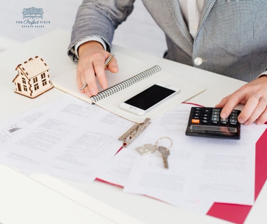 A man is sitting at a desk using a calculator and a cell phone.