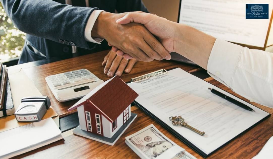 A man and woman are shaking hands over a table with a model house and money.