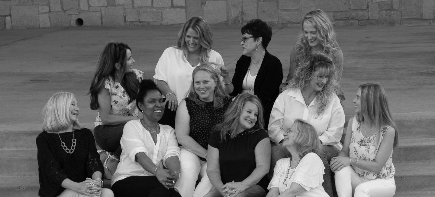 A group of women are sitting on the steps of a building.