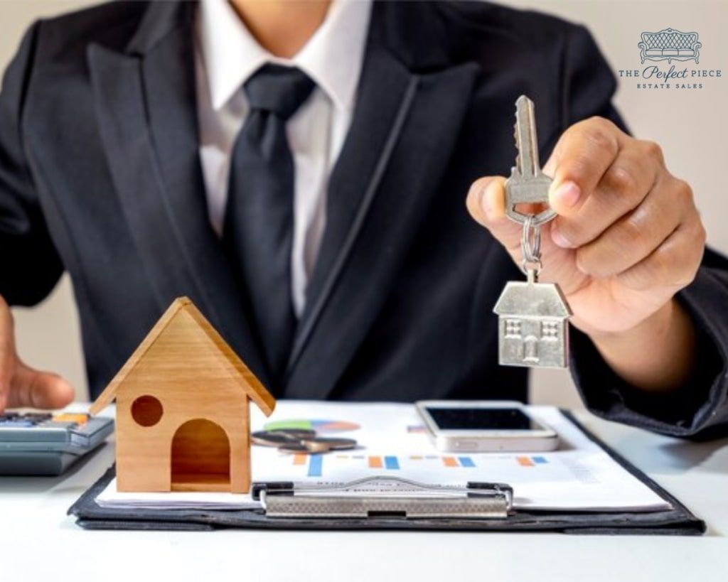 A man in a suit is holding a pair of keys next to a model house.