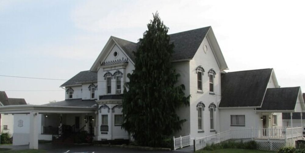 The front door of a house with a porch and plants in front of it.