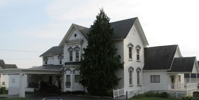 The front door of a house with a porch and plants in front of it.