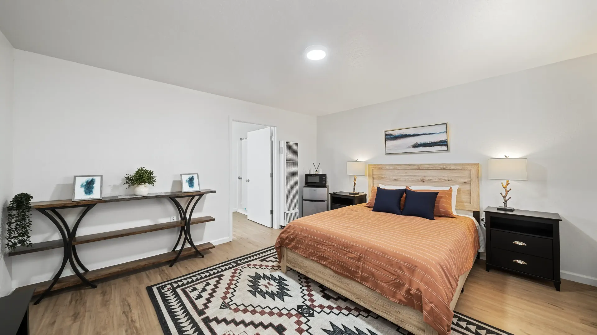 Bedroom with bed, rug, console table, and open door to the closet.
