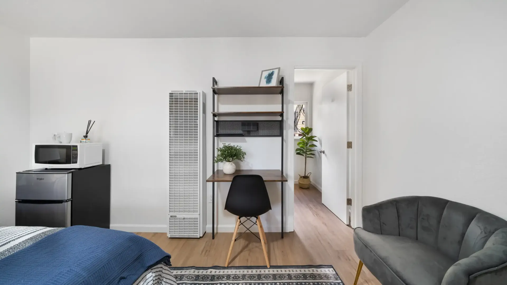 Small studio apartment with desk, seating area, and kitchenette.