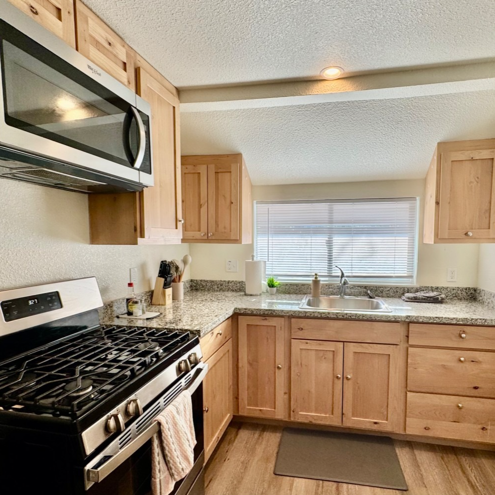 Kitchen with light wood cabinets, granite counters, and stainless steel appliances.