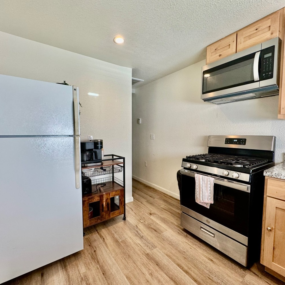 Kitchen with a refrigerator, microwave, stove, and wooden cabinets.