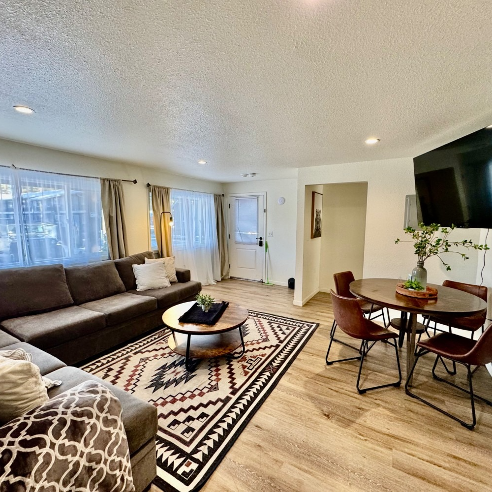 Cozy living room with brown sectional, round table, patterned rug, and TV.