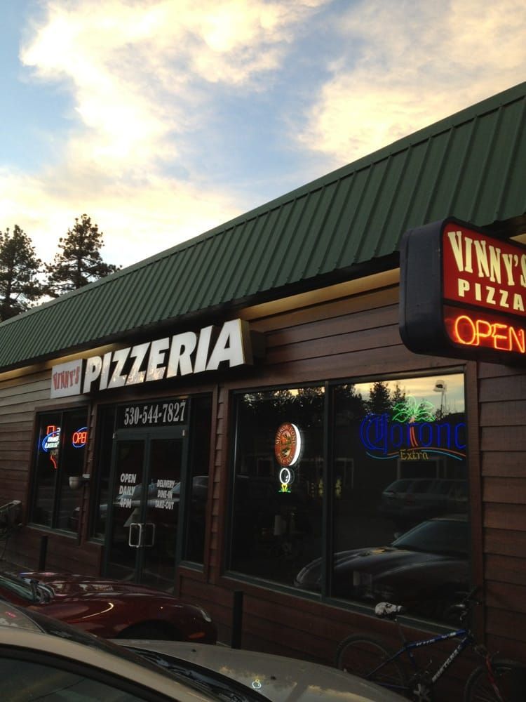 Nikky's Pizzeria storefront with neon sign, open sign, and brown wooden exterior.