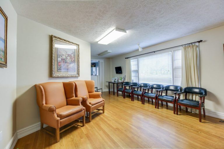 Waiting room with leather chairs, a row of chairs, and a window with blinds.
