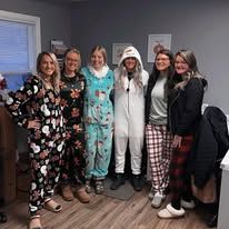 Six people in pajamas pose indoors. A mix of patterns and solid colors.