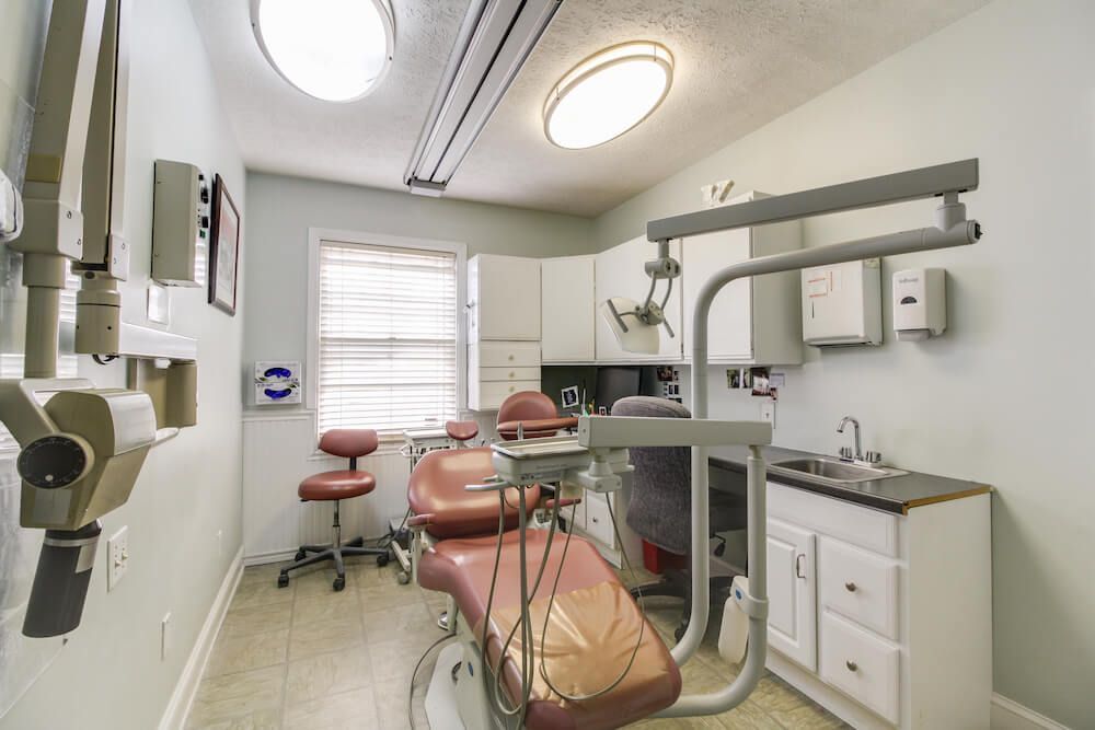 Dental office examination room with dental chair, instruments, and sink.