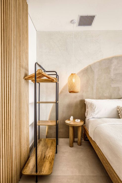 A bedroom with a textured concrete wall and a wooden bedside table.