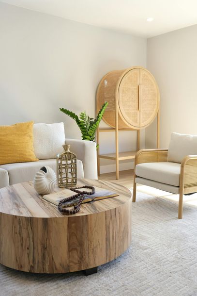 A bright living room features a round wooden coffee table.