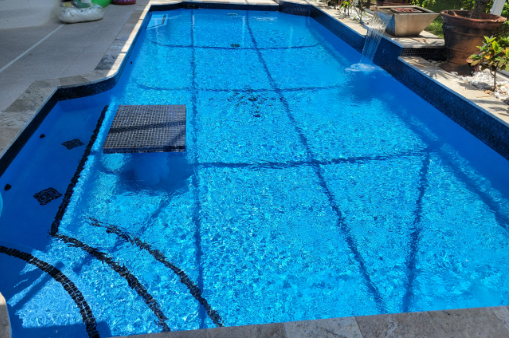 A large swimming pool with blue water and black steps