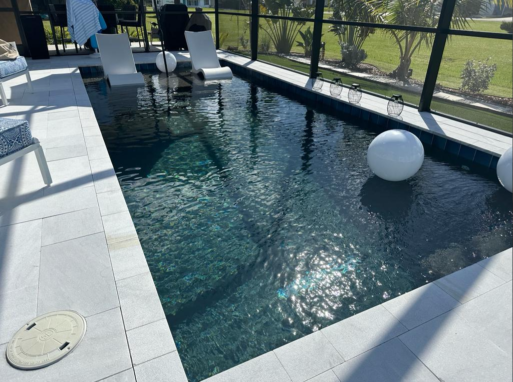 A large swimming pool is surrounded by a screened in area